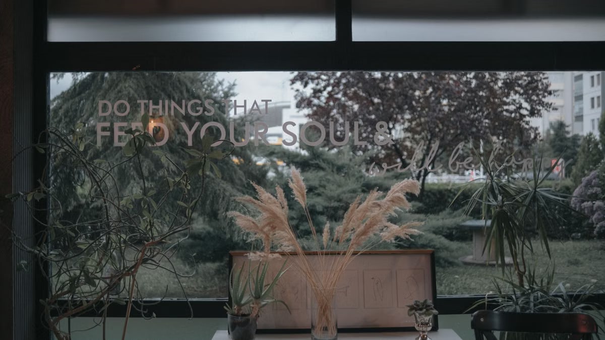 Cozy indoor setup with plants and an inspiring window quote, evoking peace.
